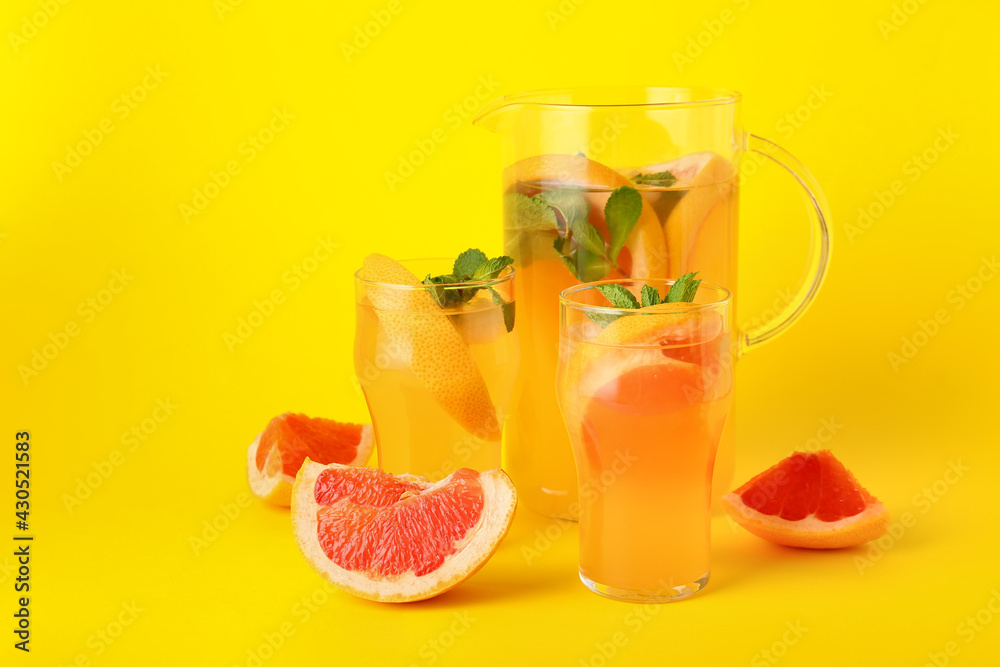 Glasses and jug of tasty grapefruit lemonade on color background Glasses and jug of tasty grapefruit lemonade on color background