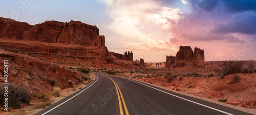Panoramic landscape view of a Scenic road in the red rock canyons. Dramatic Colorful Sunset Sky Artistic Render. Taken in Arches National Park, located near Moab, Utah, United States. photo