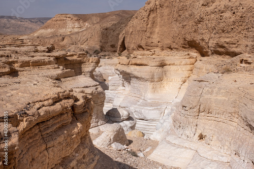 View inside a dry wadi Daras in a remote desert of the Northern Negev. Impressive white walls of a narrow winding canyon. Hiking trail in a heart of the desert. Nature reserve. photo