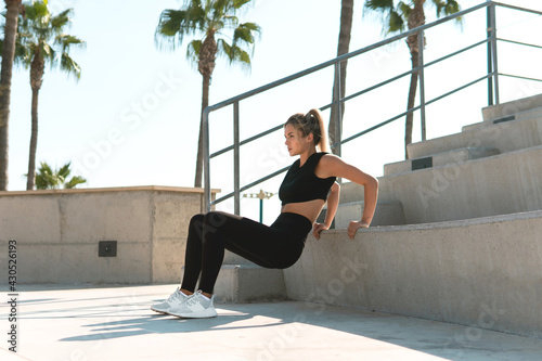 Athletic woman is doing triceps dip during summer calisthenic workout