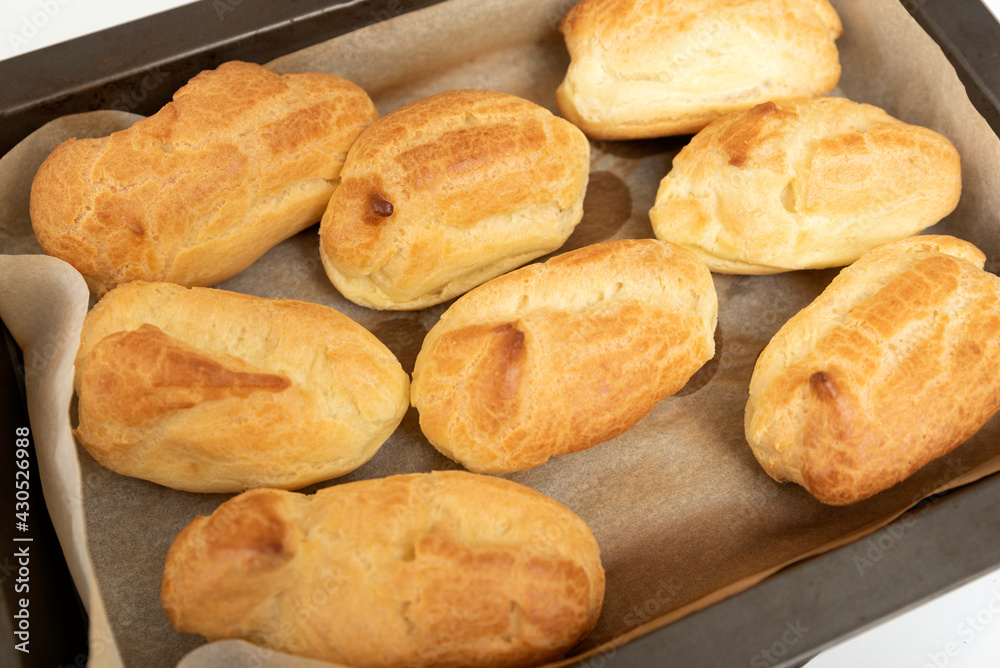 Cooking homemade profiteroles or eclair. Fresh baked goods on baking sheet. Top view.