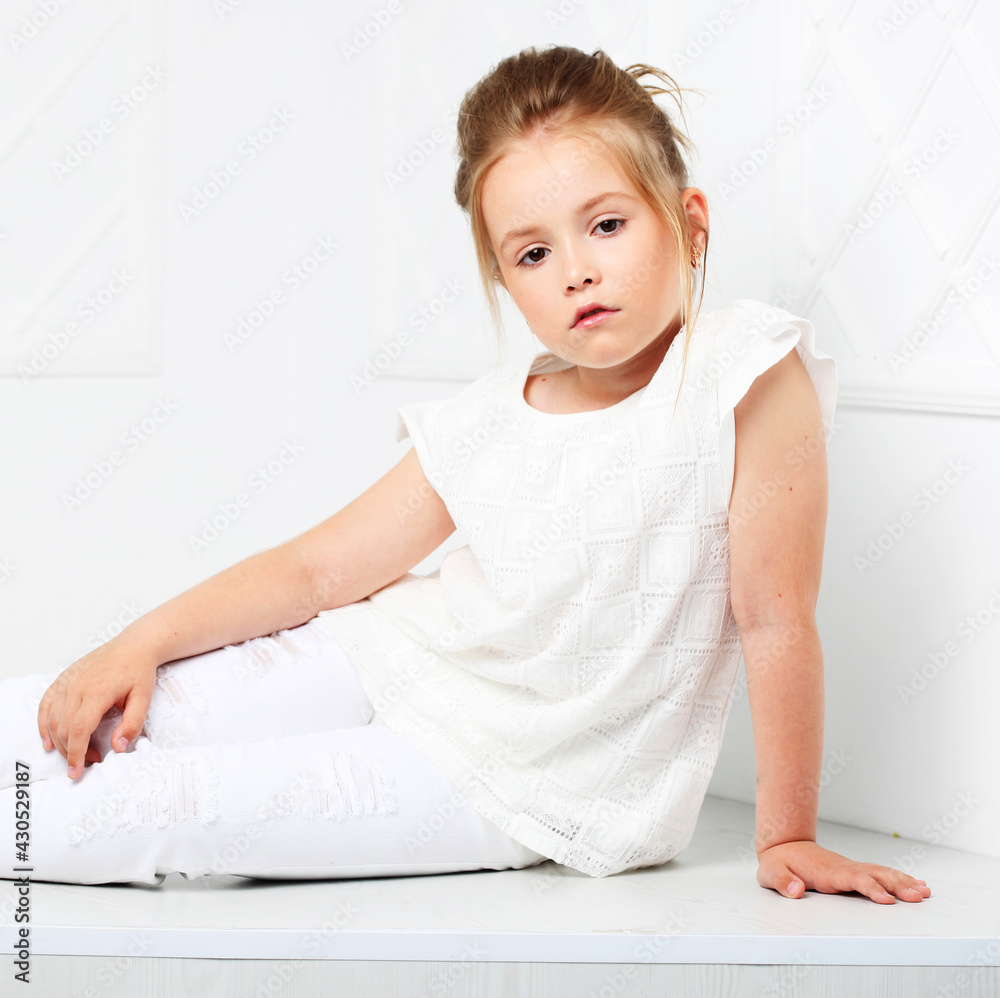 Fototapeta premium Children's fashion. Beautiful pensive serious blonde girl in whi