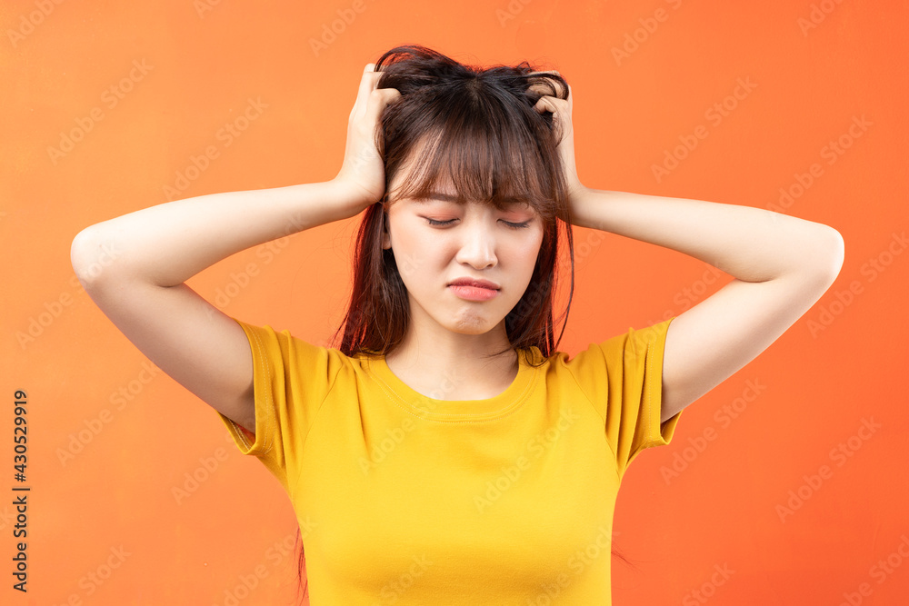 Fototapeta premium Image of young Asian woman wearing yellow t-shirt on orange background