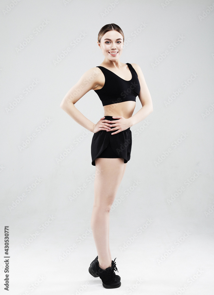 Full length of confident beautiful fitness woman standing over grey background Full length of confident beautiful fitness woman standing over grey background