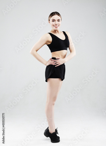 Full length of confident beautiful fitness woman standing over grey background