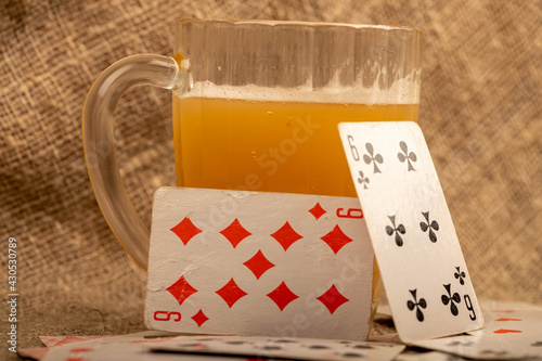 Playing cards and a glass of vodka on a table covered with coarse burlap.