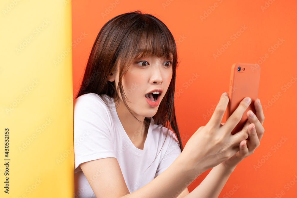 Naklejka premium Young asian girl overlapping yellow background on orange background
