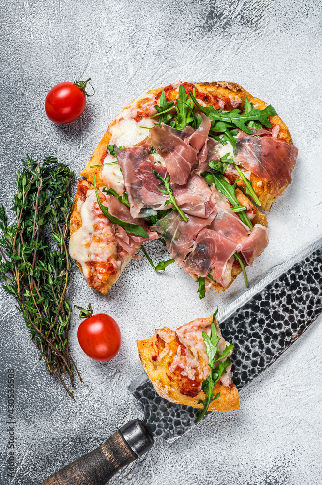 Italian Pizza with  parma ham, arugula and cheeseon a kitchen table. White background. Top view