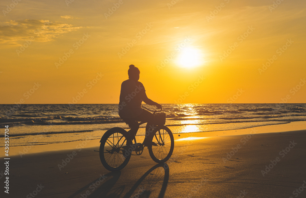 Fototapeta premium Silhouette of young woman cycling bicycle.