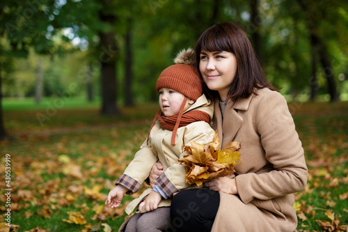 family, motherhood, love and care concept - mother and cute little daughter in autumn park or forest