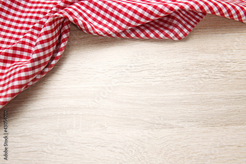 Red checered cloth on wooden table top view. Picnic towel on light wood texture background empty advertisement space.