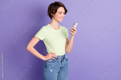 Profile side view portrait of nice focused cheerful girl holding in hands using device browsing web isolated over violet color background