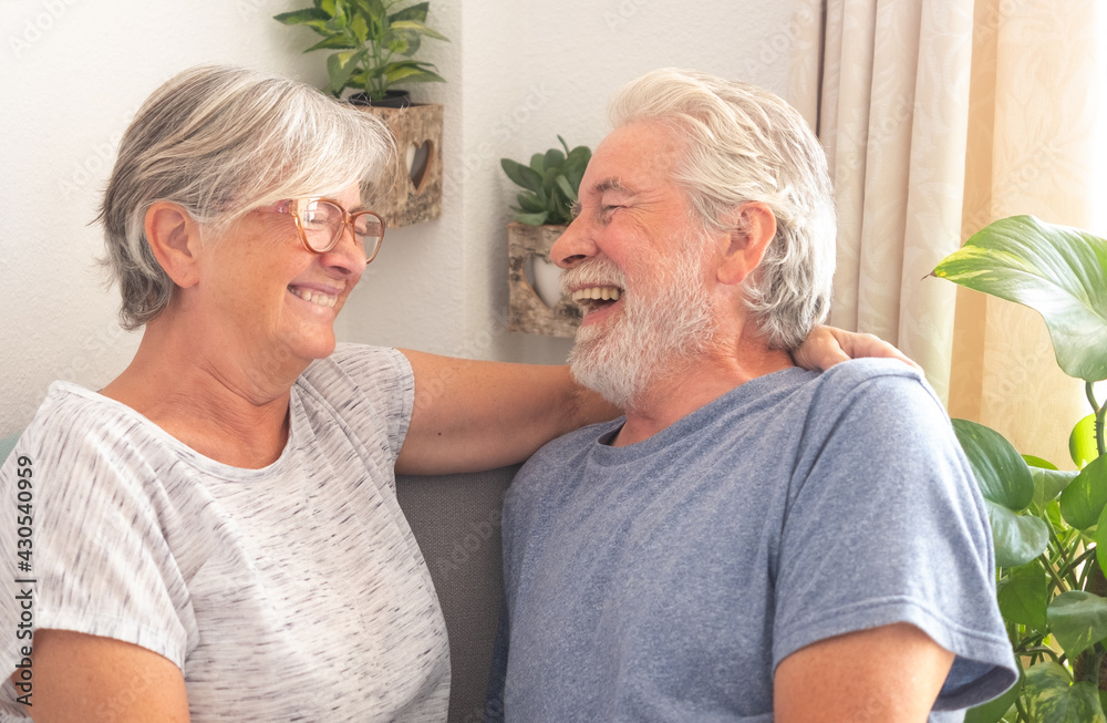 Cheerful senior couple sitting in living room at home,laughing carefree Cheerful senior couple sitting in living room at home,laughing carefree