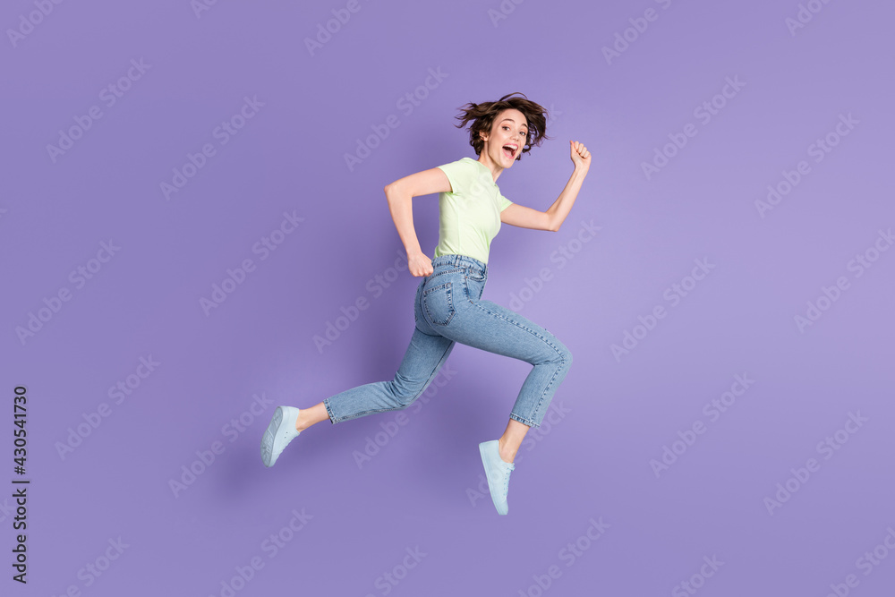 Full length body size view of lovely cheerful girl jumping having fun running fast isolated over bright violet purple color background Full length body size view of lovely cheerful girl jumping having fun running fast isolated over bright violet purple color background