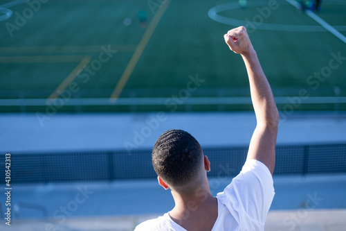 Young man celebrating victory on bleachers watching football