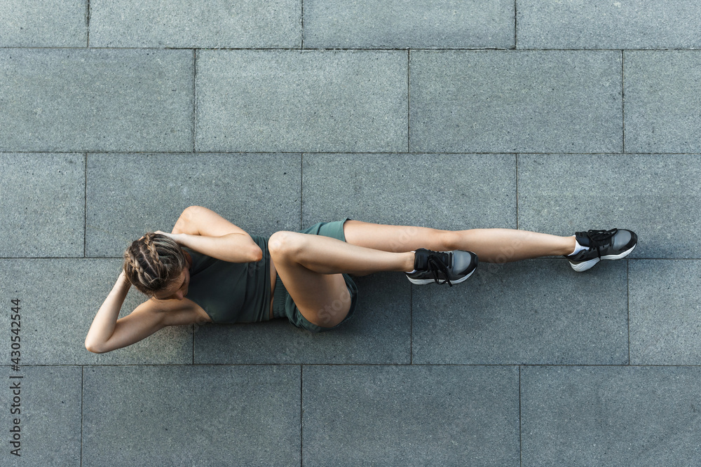 Fototapeta premium Athletic woman doing abdominal crunches exercise on concrete floor