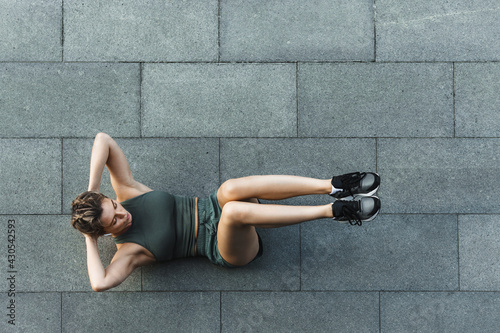 Athletic woman doing abdominal crunches exercise on concrete floor