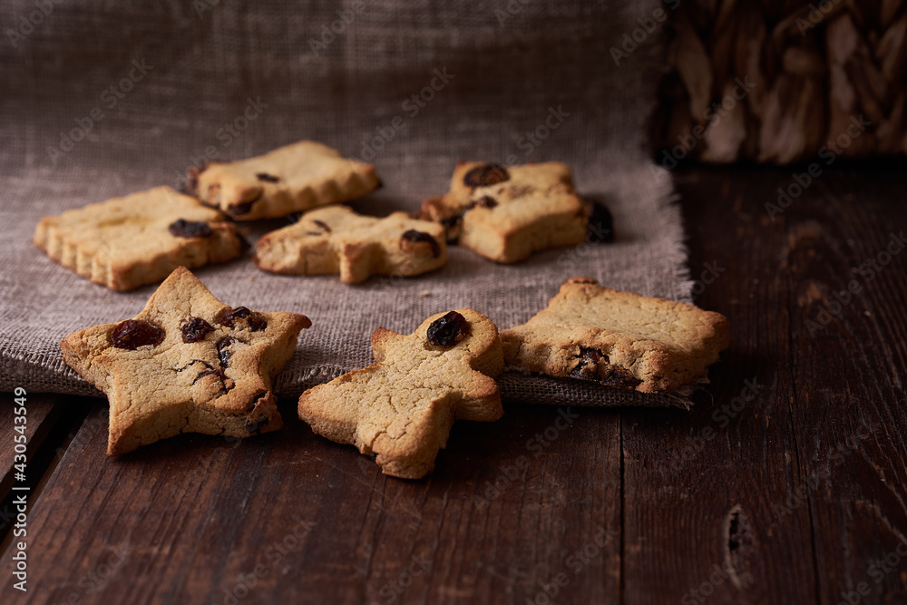 Fototapeta premium Healthy homemade gluten-free, lactose-free cookies of various shapes without sugar with raisins and chocolate on a dark brown wooden background