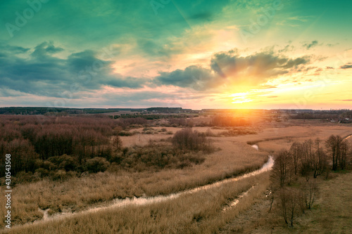 View of the countryside with winding brook and evening sky during sunset. View from above