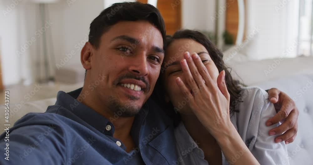 Romantic hispanic couple embracing sending kisses on sofa in living room Romantic hispanic couple embracing sending kisses on sofa in living room