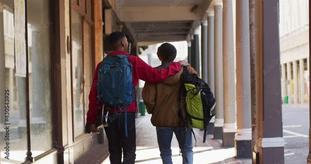 Back view of mixed race gay male couple talking and smiling in the street Back view of mixed race gay male couple talking and smiling in the street