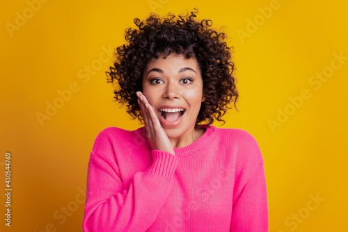 Young woman excited face touch cheek on yellow background