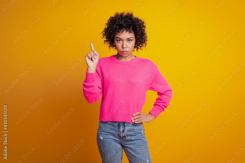 Portrait of strict girl posing hand hip raise finger negative signal on yellow wall