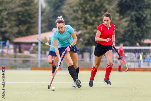Two field hockey female players struggle for ball