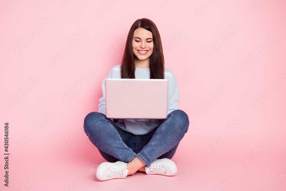 Full size photo of nice optimistic brunette hairdo lady sit type laptop wear shirt jeans sneakers isolated on pink color background Full size photo of nice optimistic brunette hairdo lady sit type laptop wear shirt jeans sneakers isolated on pink color background