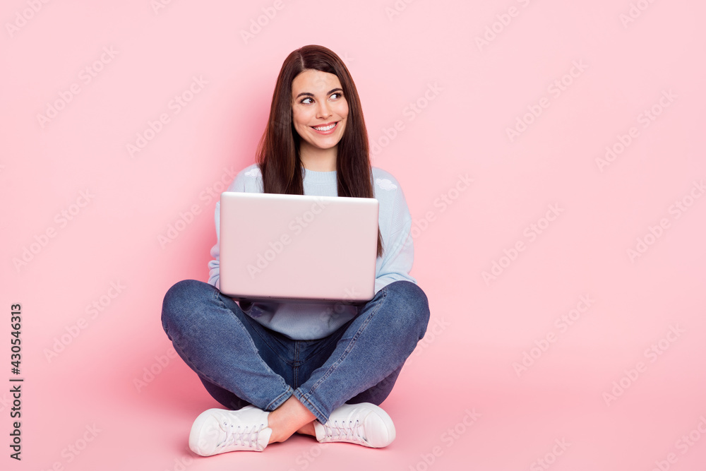 Full size photo of young happy smiling dreamy girl look copyspace sit floor work in laptop isolated on pink color background Full size photo of young happy smiling dreamy girl look copyspace sit floor work in laptop isolated on pink color background
