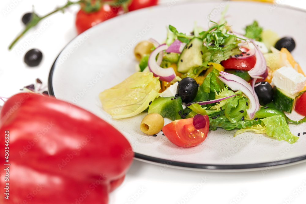Close up of delicious vegetables salad with appetizing tomatoes,olives,greens,onions and feta cheese on white background. Concept of proper nutrition for weight loss. Close up of delicious vegetables salad with appetizing tomatoes,olives,greens,onions and feta cheese on white background. Concept of proper nutrition for weight loss.