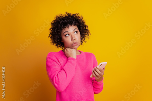 Portrait of lovely cheerful girl holding telephone look up empty space have doubts