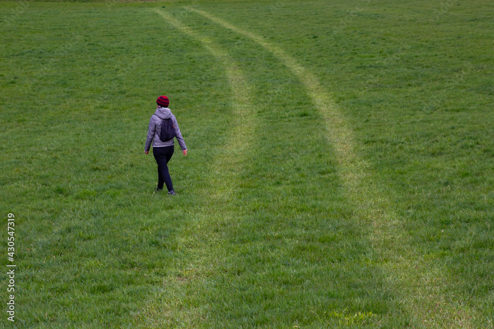 Unidentifiable woman walking in the grass, leaving the trail Unidentifiable woman walking in the grass, leaving the trail