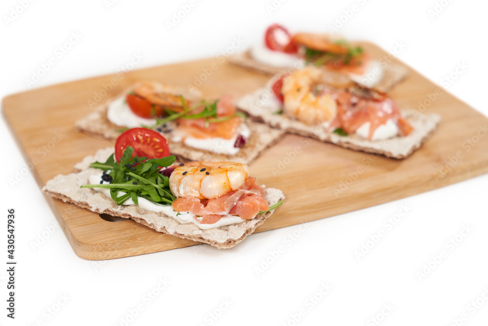 Close up of appetizing diet breads with shrimp, salmon and tomatoes,arugula on wooden board. Concept of tasty and healthy food for weight maintenance and weight loss. Close up of appetizing diet breads with shrimp, salmon and tomatoes,arugula on wooden board. Concept of tasty and healthy food for weight maintenance and weight loss.