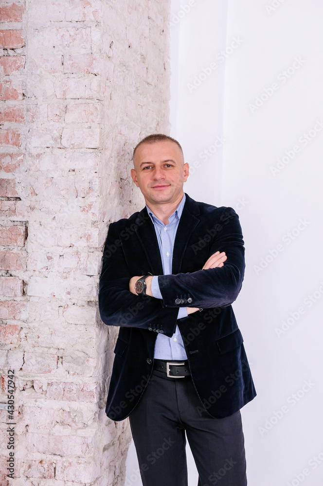 Man in blue shirt, black trousers and blue jacket on brick wall background Man in blue shirt, black trousers and blue jacket on brick wall background