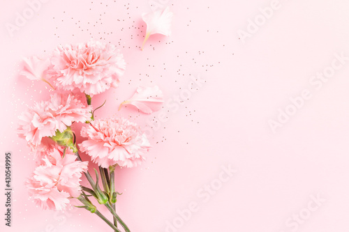 Pink carnations on pink background with confetti. © Olga Zarytska
