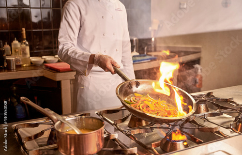 Person using flambe procedure while cooking vegetables