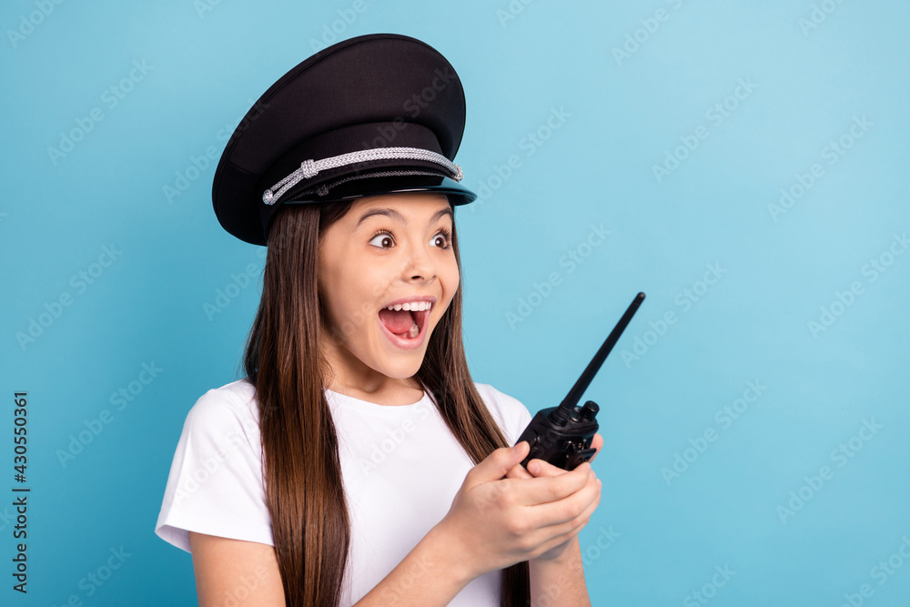 Portrait of attractive overjoyed amazed cheerful girl wearing hat using radio set isolated over bright blue color background Portrait of attractive overjoyed amazed cheerful girl wearing hat using radio set isolated over bright blue color background