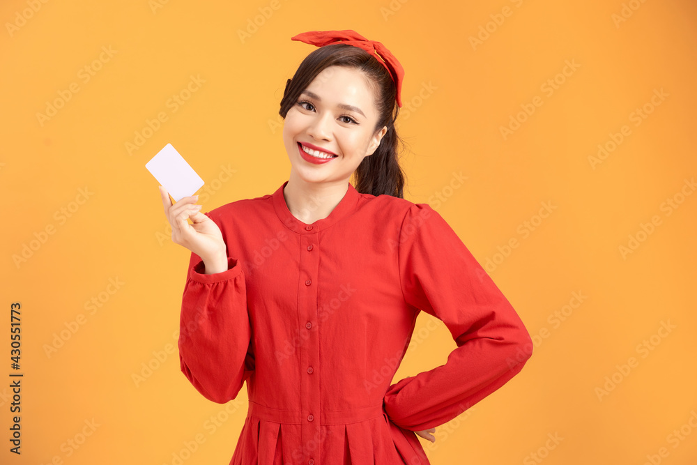 Portrait of a young woman showing credit card and looking isolated over yellow background Portrait of a young woman showing credit card and looking isolated over yellow background