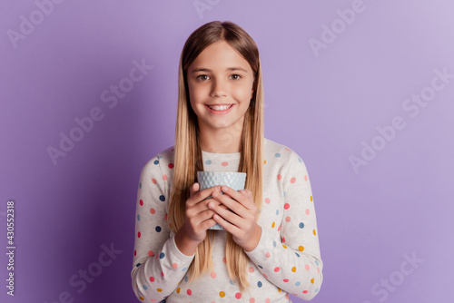 Little smiling girl hold coffee cup isolated on violet background