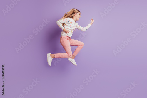 Cheerful kid girl jump run isolated over violet background