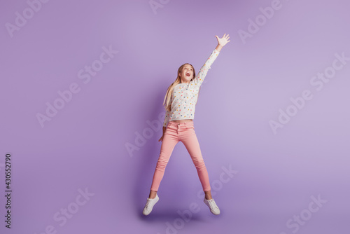 Small girl jump up catch isolated on purple background