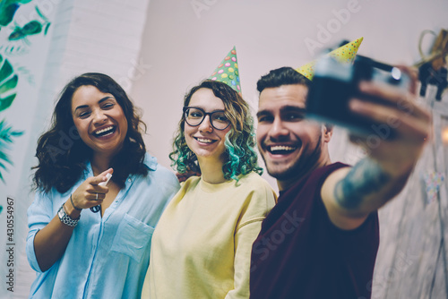 Emotional happy group of birthday guests making selfie on camera enjoying holiday entertaining, excited young women and man posing for common picture during celebration laughing and joking together