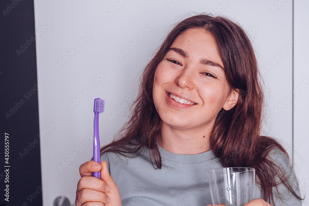 Young cheerful girl holding toothbrush and smiling. Morning routine concept Young cheerful girl holding toothbrush and smiling. Morning routine concept
