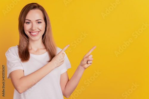 Young elegant woman direct finger empty space on yellow background