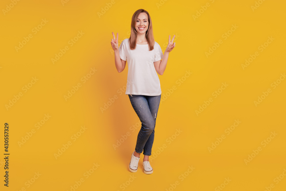 Young girl show victory sign isolated on yellow background Young girl show victory sign isolated on yellow background