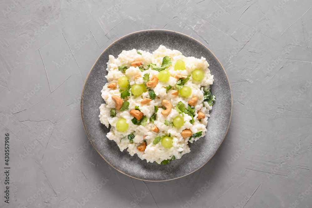 Curd Rice with cashews, grapes, cilantro on a grey background. Top view. Indian South cuisine