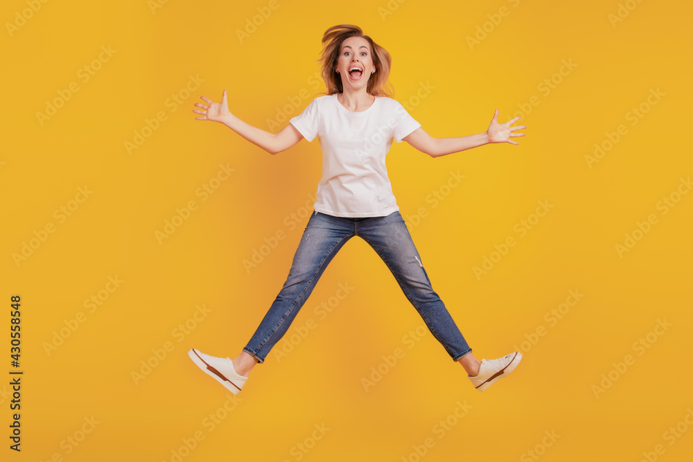 Smiling excited crazy funky girl jumping open mouth on yellow background