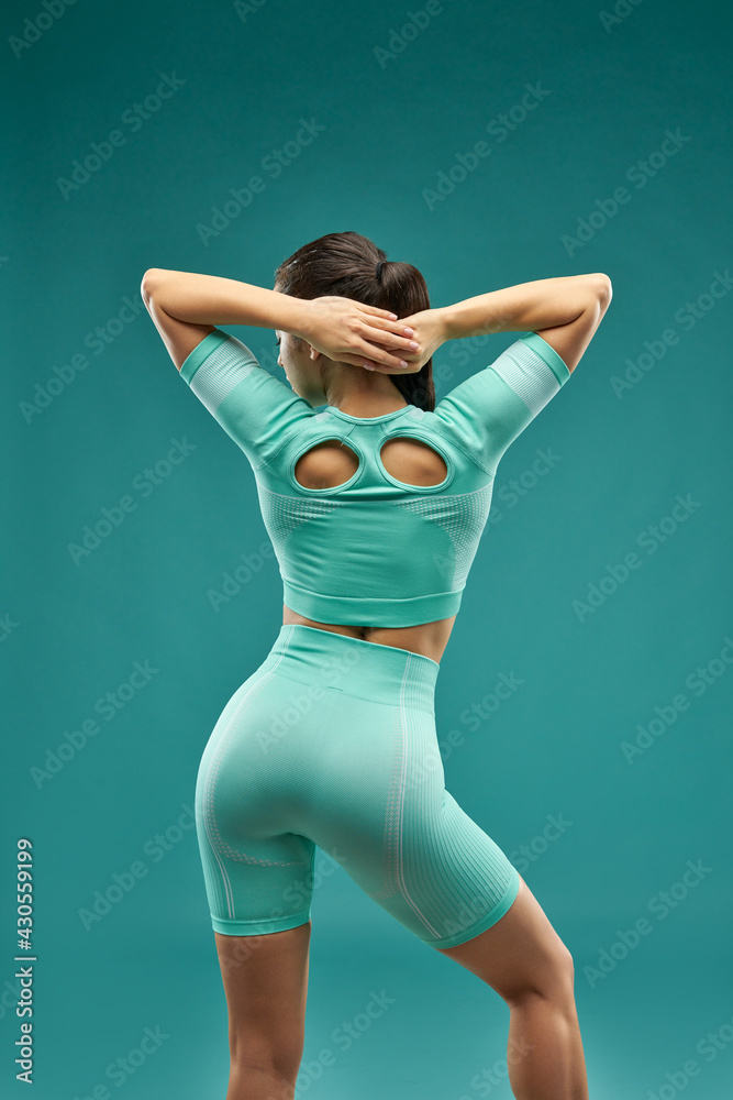 Fit young woman standing against green background