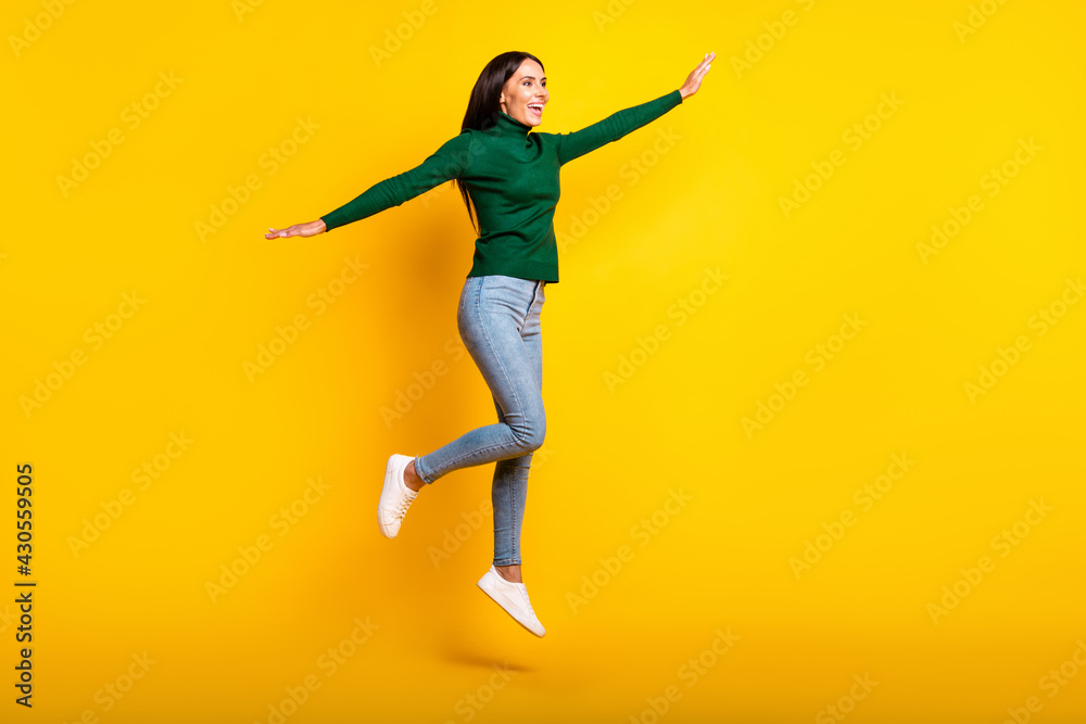 Full size profile side photo of charming happy woman jump up make hands wings isolated on yellow color background